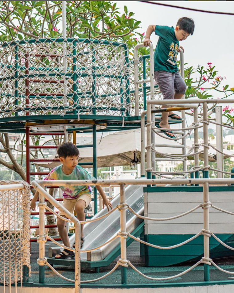 Two kids playing on a slide

Description automatically generated