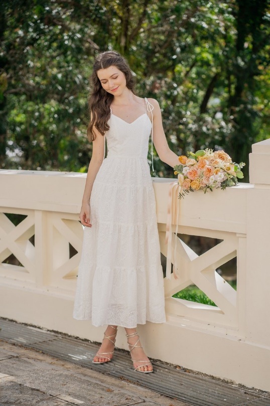 A person in a white dress holding a bouquet of flowers

Description automatically generated