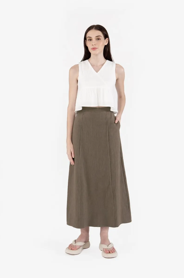 A person in a white shirt and brown skirt

Description automatically generated