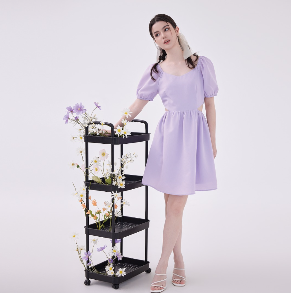 A person standing next to a black metal shelf with flowers

Description automatically generated